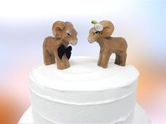 two wooden elephants standing on top of a white cake