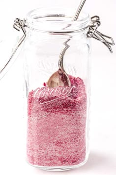 a glass jar filled with pink glitter and a spoon