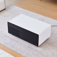 a white and black projector sitting on top of a rug in a living room