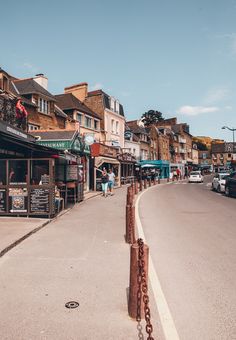 an empty street with cars parked on both sides and people walking down the sidewalk in front