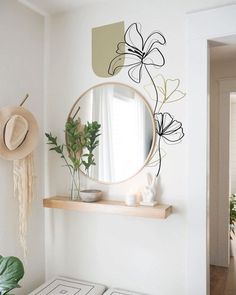 a mirror on the wall above a table with some plants in it and a hat