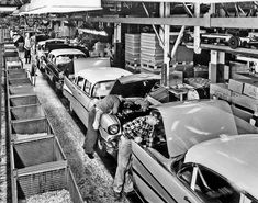 an old black and white photo of people working on cars in a car assembly line