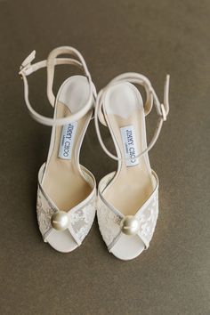 a pair of white shoes with bows and pearls