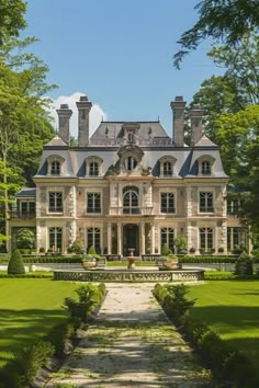 a large house with lots of windows in the front yard and landscaping around it, surrounded by lush green trees