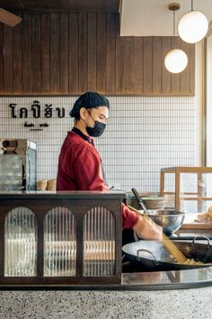 a woman wearing a face mask cooking in a restaurant