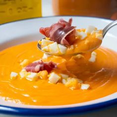 a spoon full of soup with bacon and cheese on it, being held by someone