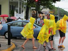 three people in yellow raincoats crossing the street