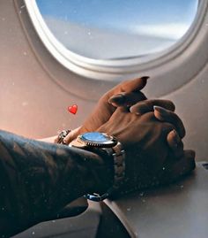 two hands holding each other while sitting on an airplane