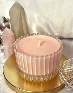 a pink candle sitting on top of a gold plate