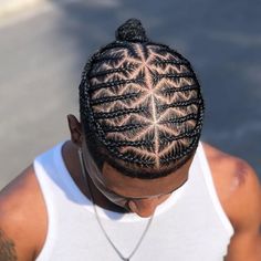 a man with braids on his head is looking down at the ground while wearing a white tank top