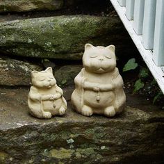 two ceramic cats sitting on some steps