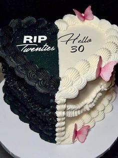 a black and white cake with pink butterflies on it's side, sitting on a plate