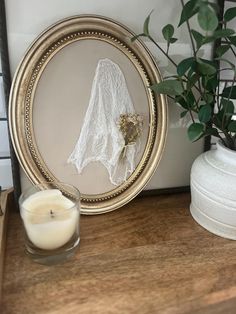 a candle sits on a table next to a lace doily and a potted plant