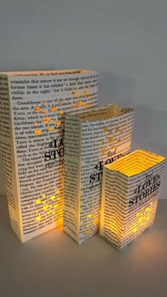 three lit up books sitting next to each other on top of a table in front of a white wall