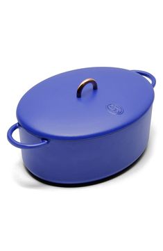 a blue casserole on a white background with the lid open and a gold handle