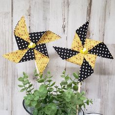 two black and yellow pinwheels sitting next to a potted plant