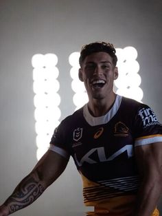 a rugby player with his arms spread out in front of the camera, smiling and looking at the camera