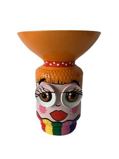 a ceramic vase with an artistic face painted on it's front and sides, sitting against a white background