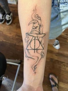 a tattoo on the arm of a person with a harry potter hat and lightning bolt