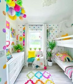 a room with bunk beds and colorful decorations on the walls, along with white drawers