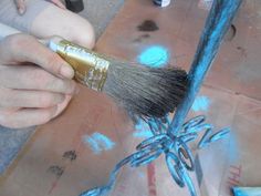 a person holding a brush with blue paint on it