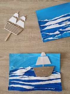 some paper plates with boats on them sitting on a wooden table next to other pieces of art