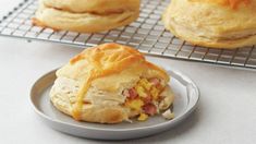 two pastries sitting on top of a plate next to a cooling rack filled with muffins