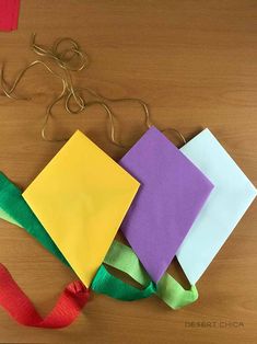 four different colored pieces of paper tied together on a wooden table next to a string