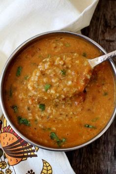 a spoon full of soup sitting on top of a table next to some napkins