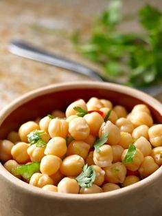 a bowl filled with chickpeas and garnished with cilantro leaves