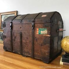 an old wooden trunk sitting on top of a hard wood floor next to a globe