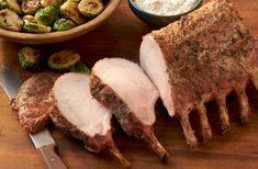 sliced pork with brussel sprouts on the side next to a bowl of vegetables