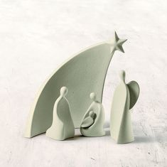 a ceramic nativity scene with a star on the top and two people standing next to it