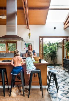 two children and an adult are sitting at the kitchen counter in front of their dog