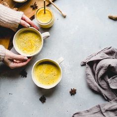 two people holding mugs filled with yellow liquid