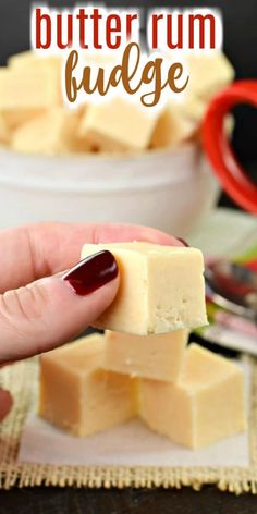 a hand holding a piece of butter rum fudge in front of a white bowl