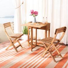 a table and two chairs in front of a window with the ocean view behind them