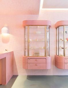 a pink room with two display cases in it