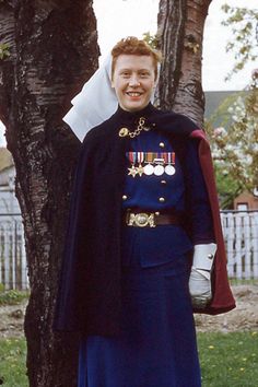 a man in uniform standing next to a tree