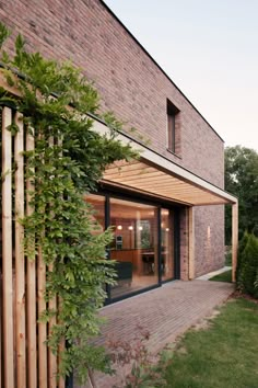 a brick building with an open patio and wooden slats on the outside, surrounded by greenery