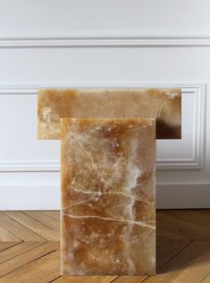 a marble block sitting on top of a wooden floor next to a white painted wall