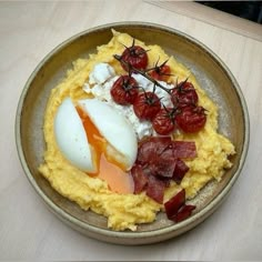 a brown plate topped with eggs, bacon and tomatoes on top of mashed potatoes