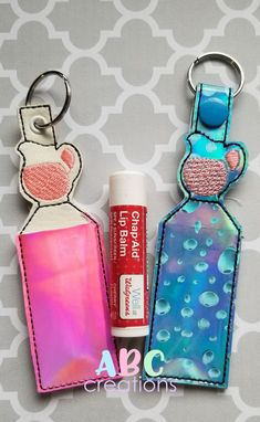 two keychains with different designs on them and one has a lip bale in it