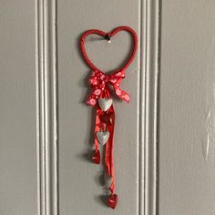 a red heart hanging from the side of a white door with a bow on it