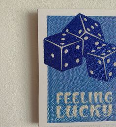 two blue dices with the words feeling lucky on them are hanging from a white wall