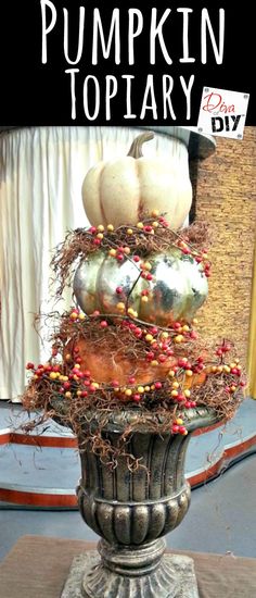 a vase filled with pumpkins and berries on top of a stone pedestal in front of a window