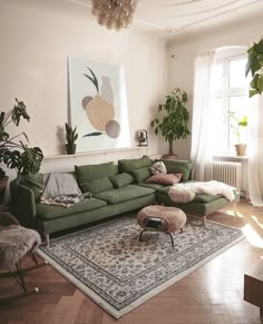 a living room with green couches and rugs on the floor in front of a large window