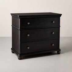 a black dresser with three drawers on one side and two knobs on the other