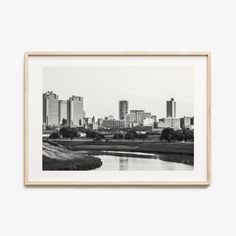 a black and white photo of a city with tall buildings in the background, framed on a wall