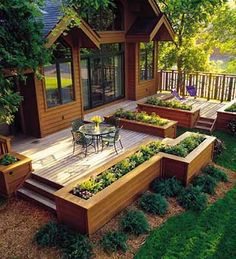 a wooden deck with raised planters on it and an outside dining area in the background